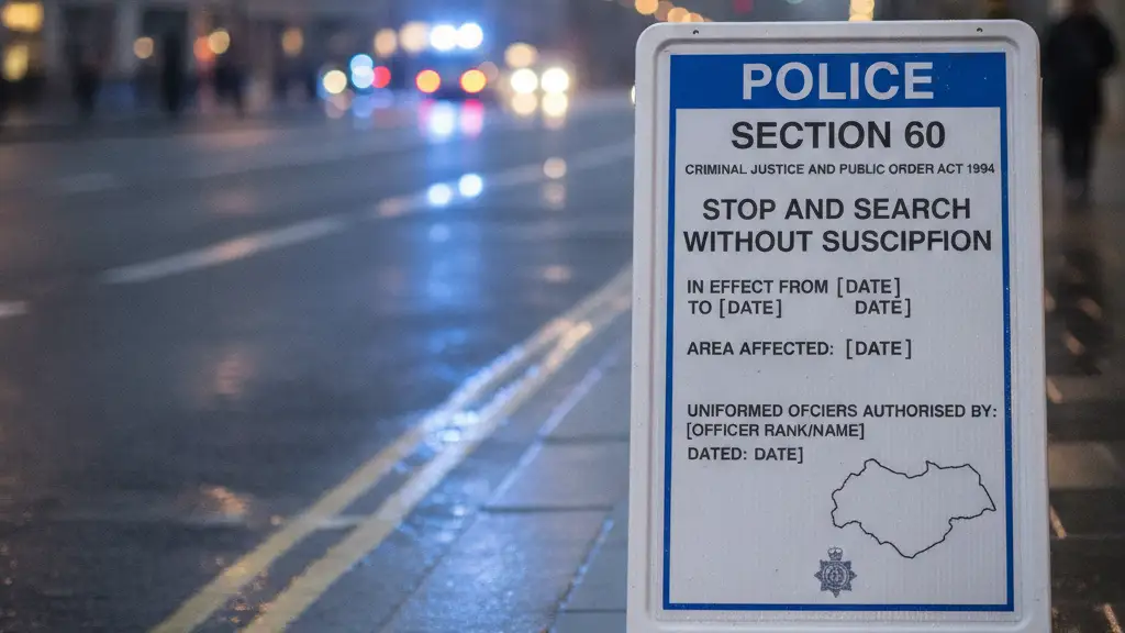 Police Section 60 order sign with blurred emergency lights reflecting on wet pavement.
