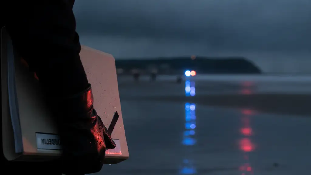Police officer's hand on a confidential file, with blurred emergency lights on a beach.