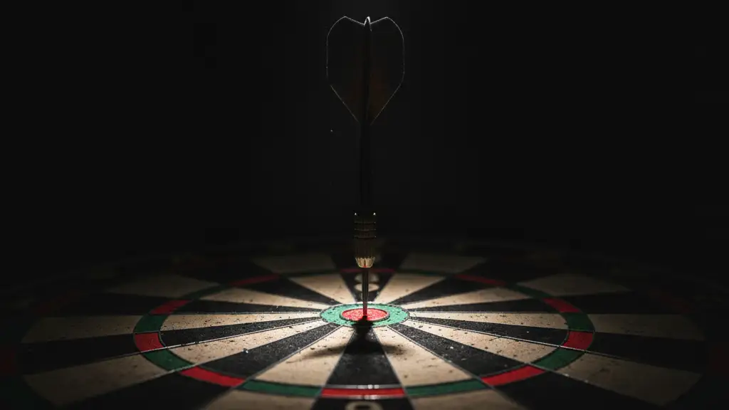 A single dart perfectly embedded in the bullseye of a dartboard, dramatically lit.