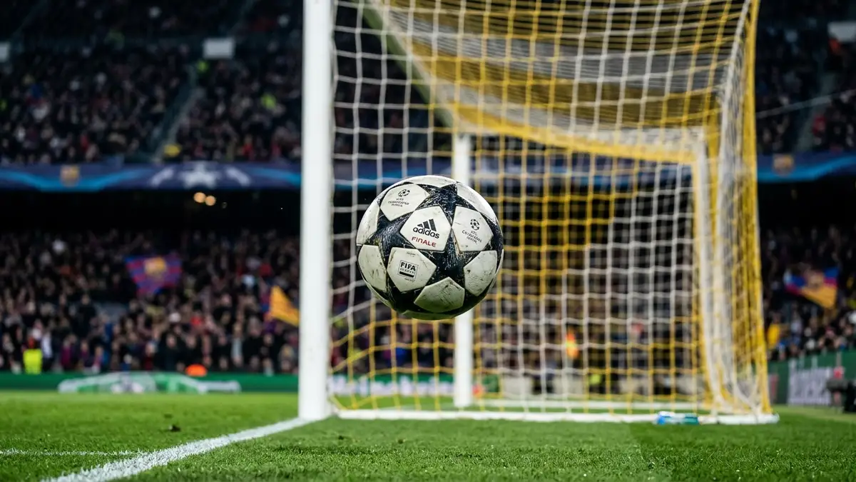 Football suspended above a goal line, blurred stadium crowd in background.