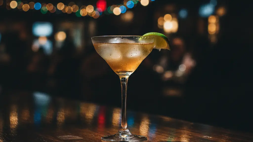 Elegant cocktail glass on a bar, blurred festive restaurant lights in background.