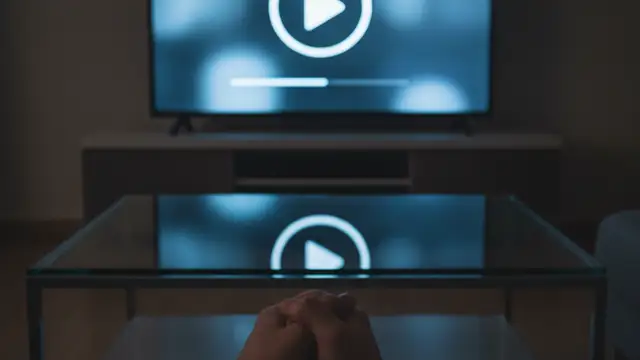 A television screen showing a documentary menu reflecting on a table in a dark room.