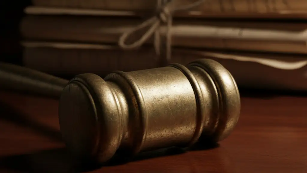 A brass gavel rests on a dark wooden surface next to old legal documents.