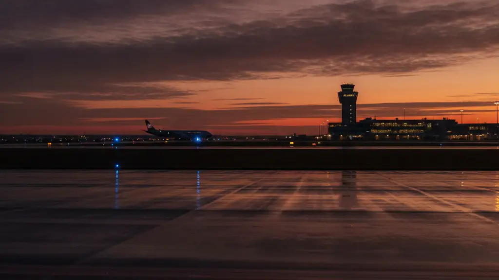 Emergency lights reflect on a wet airport runway with a distant, stationary aircraft.