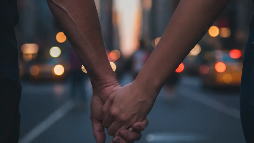 Two hands, one older, one younger, clasped together, walking in New York City.