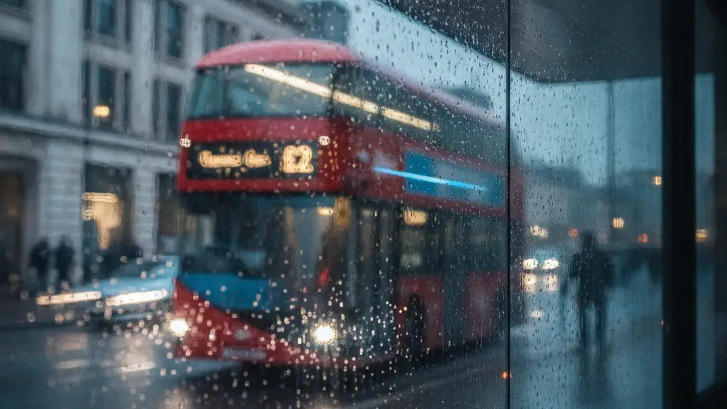 Red double-decker bus with '£2' fare, blurred through a rain-streaked window.