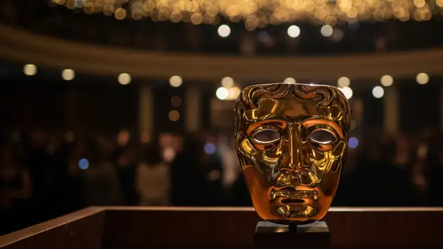 Golden BAFTA mask award on a dark podium, blurred elegant background.