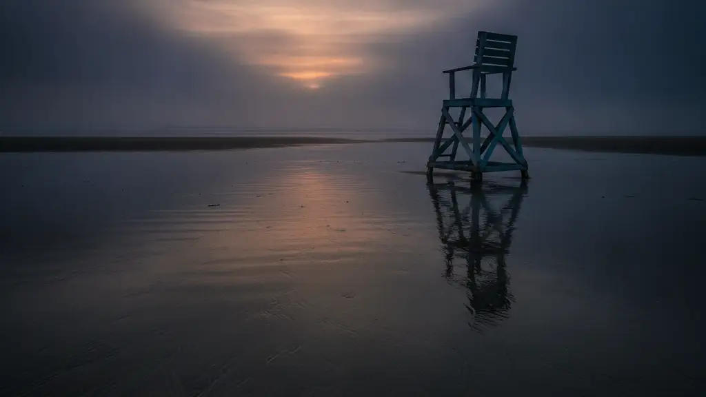 Empty lifeguard chair on a misty beach at dusk with a child's shovel.