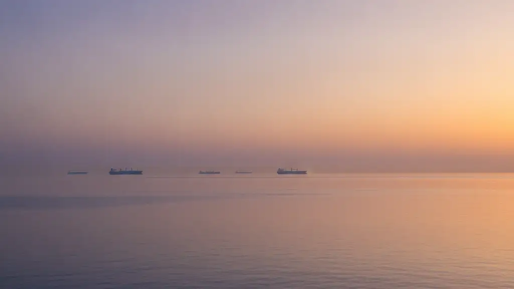 Sunrise over the Strait of Hormuz with distant cargo ships, reflecting a tense geopolitical situation.