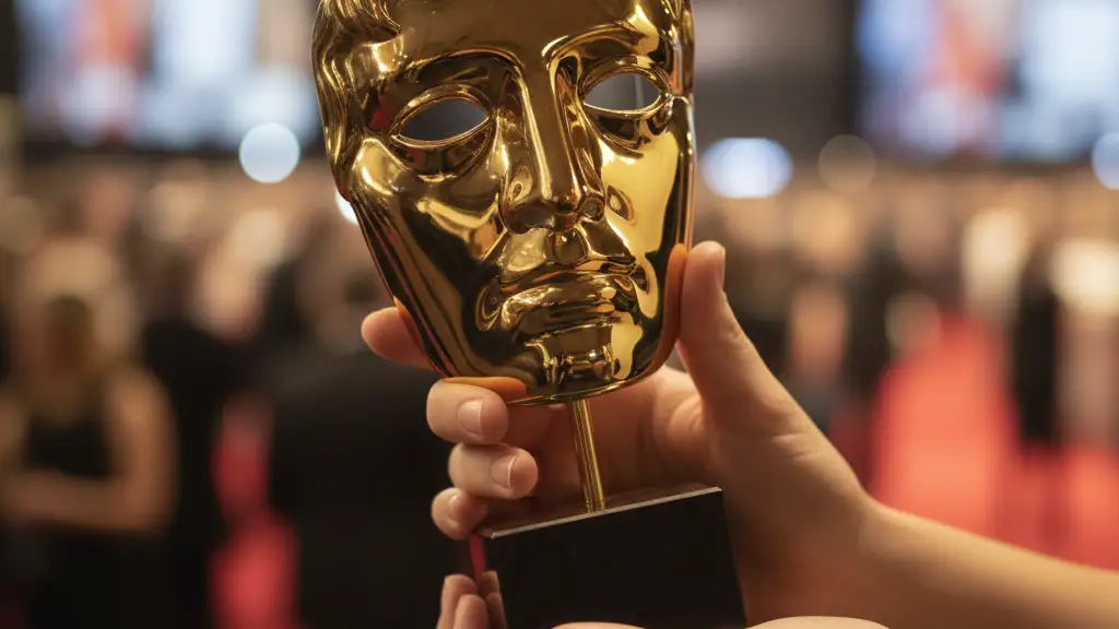 Close-up of a golden BAFTA award statuette held by hands, blurred elegant background.