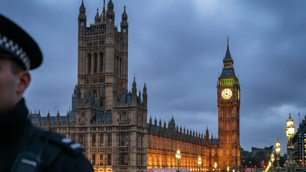The Palace of Westminster at dusk with a blurred police silhouette in the foreground.