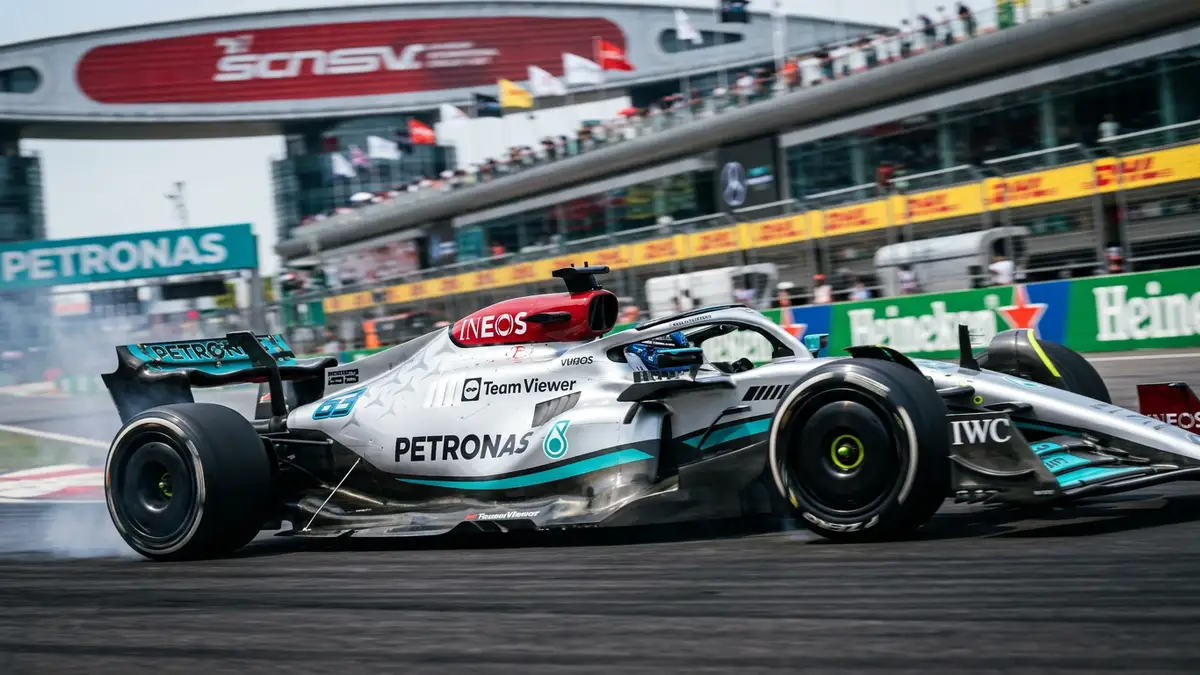 A silver Formula One car speeding past a blurred grandstand at the Shanghai International Circuit.