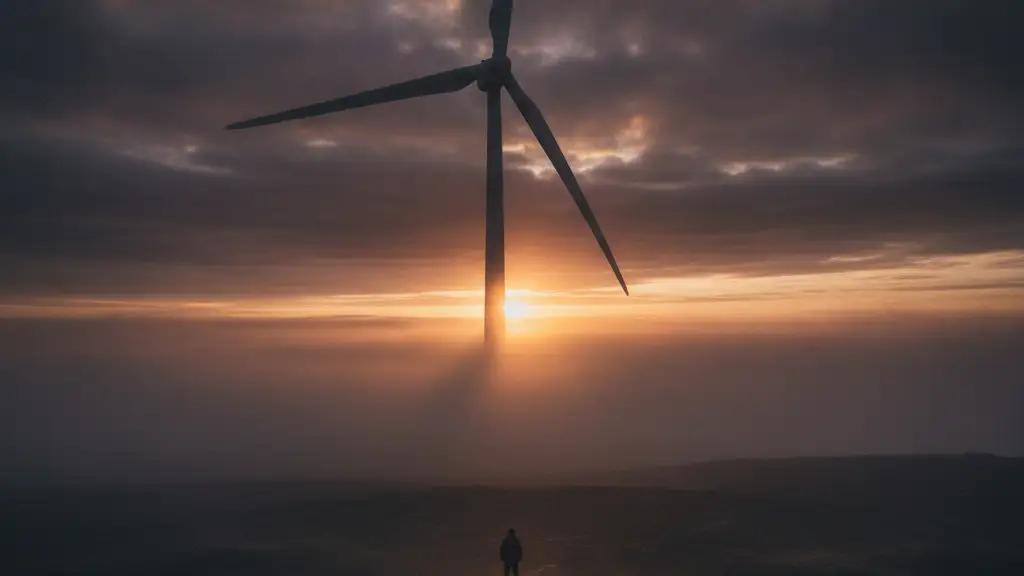 Giant wind turbine blade shrouded in mist at dawn, a figure looking up.