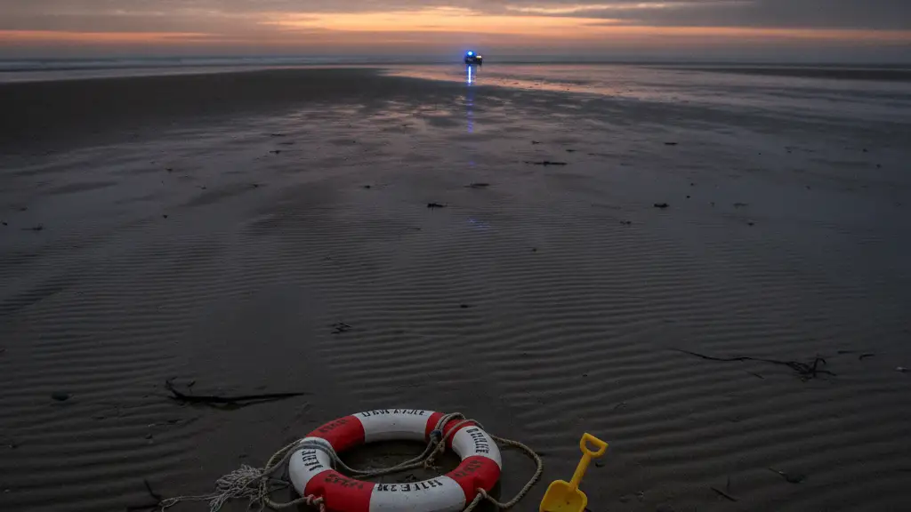 Desolate beach at dusk with a lifebuoy and child's shovel in the sand.