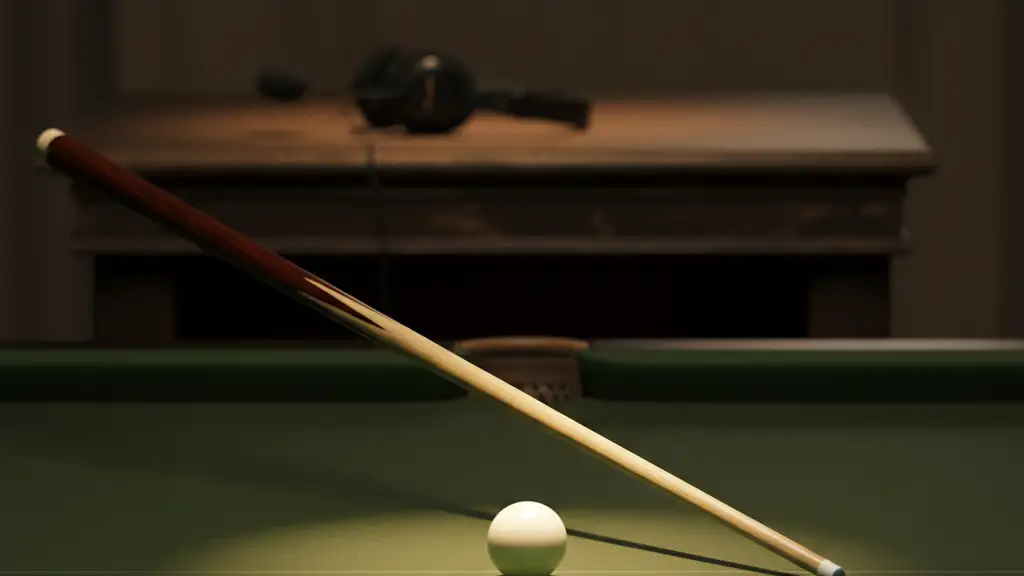 A snooker cue and white ball on a green table under a single spotlight.