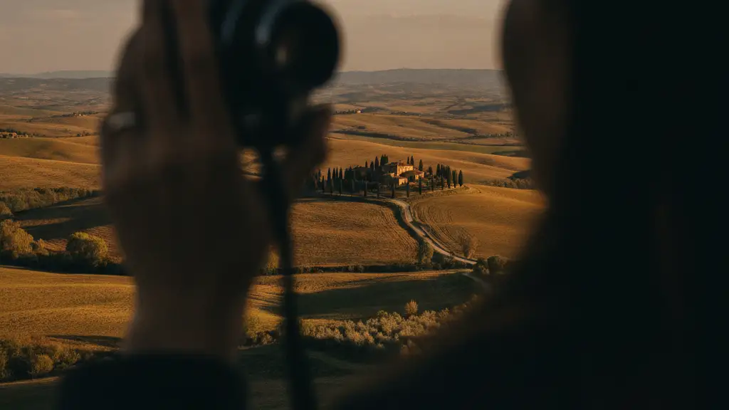 Blurred hand holding a camera, distant European landscape in soft focus.