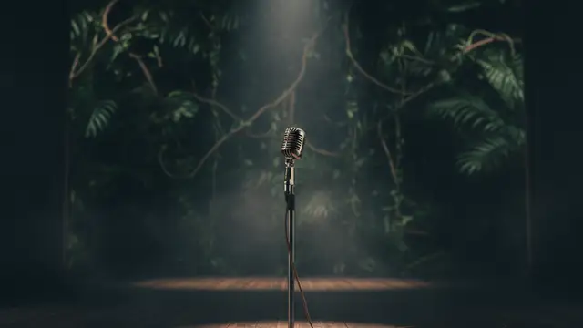 An empty microphone stand on a stage, with jungle foliage blurred in the background.