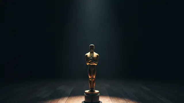 A lone Oscar statuette on a dimly lit, empty wooden stage.