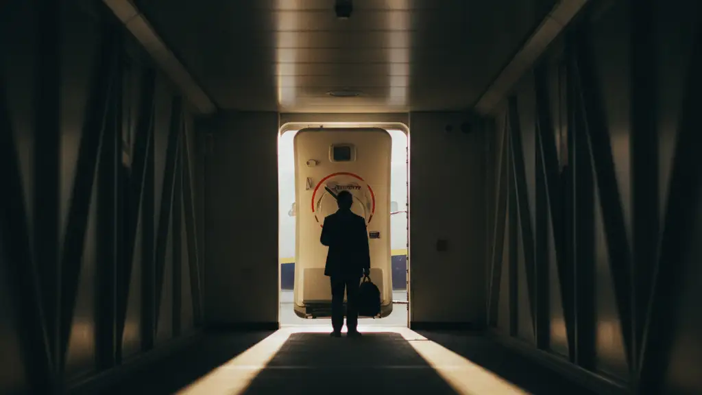 Silhouette of a passenger looking at a closed airplane door on an empty jet bridge.