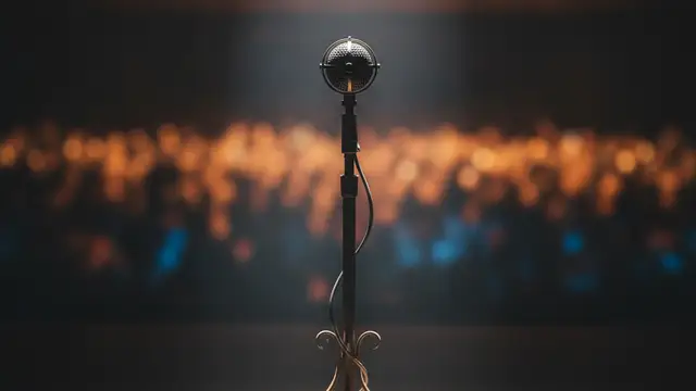 Ornate microphone stand under spotlight on an empty, dark stage.