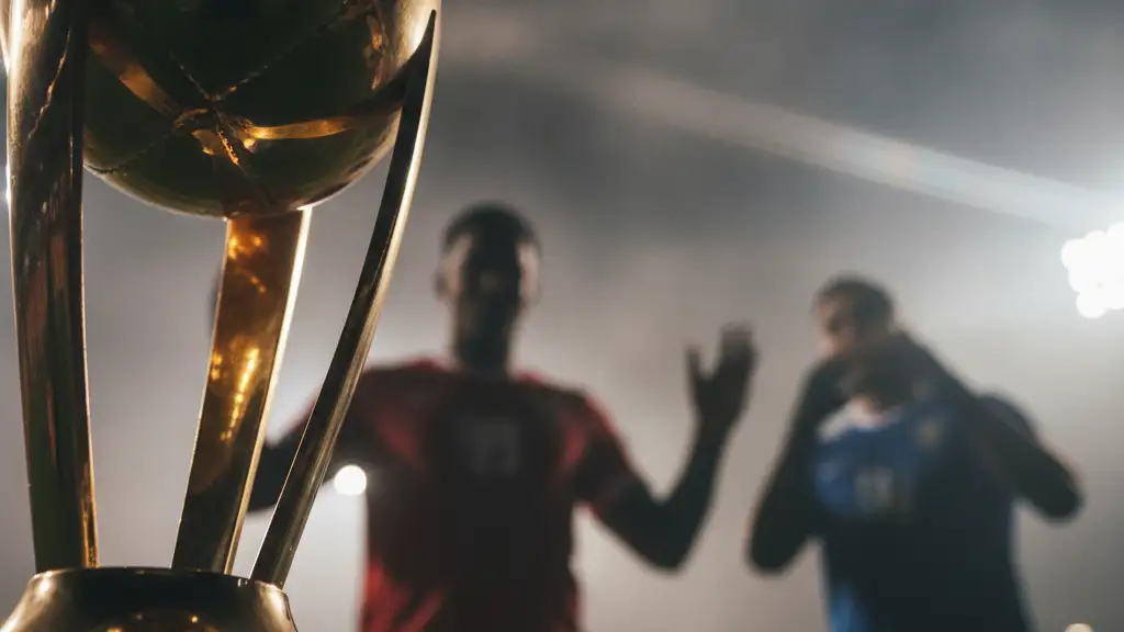 Bronze football trophy with blurred silhouettes of two players in the background.