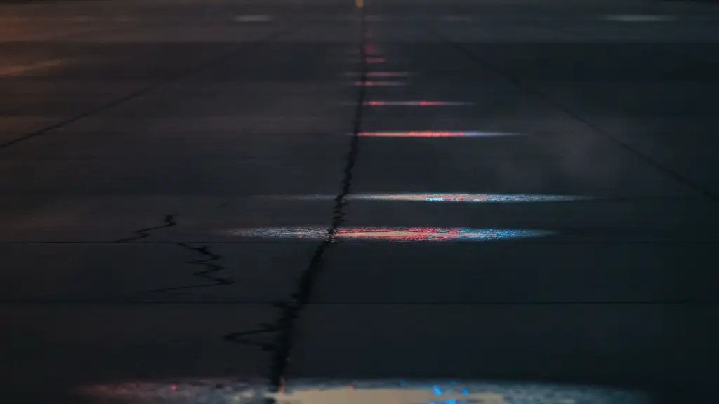 Heat haze on tarmac with blurred airplane silhouette and emergency light reflections.