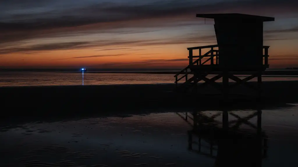 Empty lifeguard stand at twilight on a desolate beach, faint blue light reflection.
