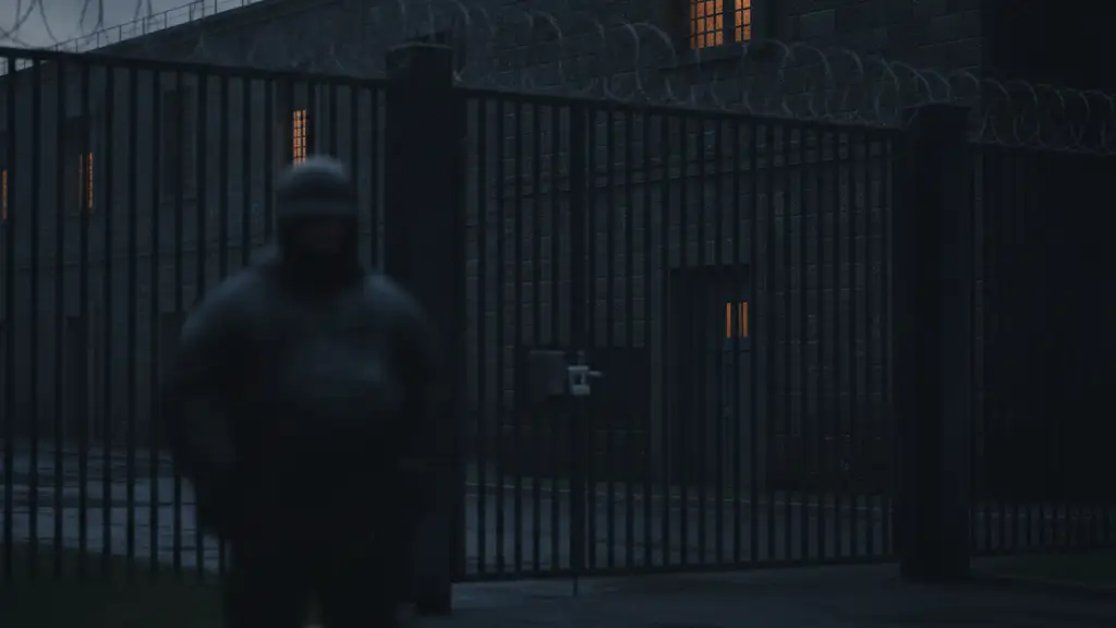 Exterior of a high-security psychiatric hospital at dusk with a barred window.