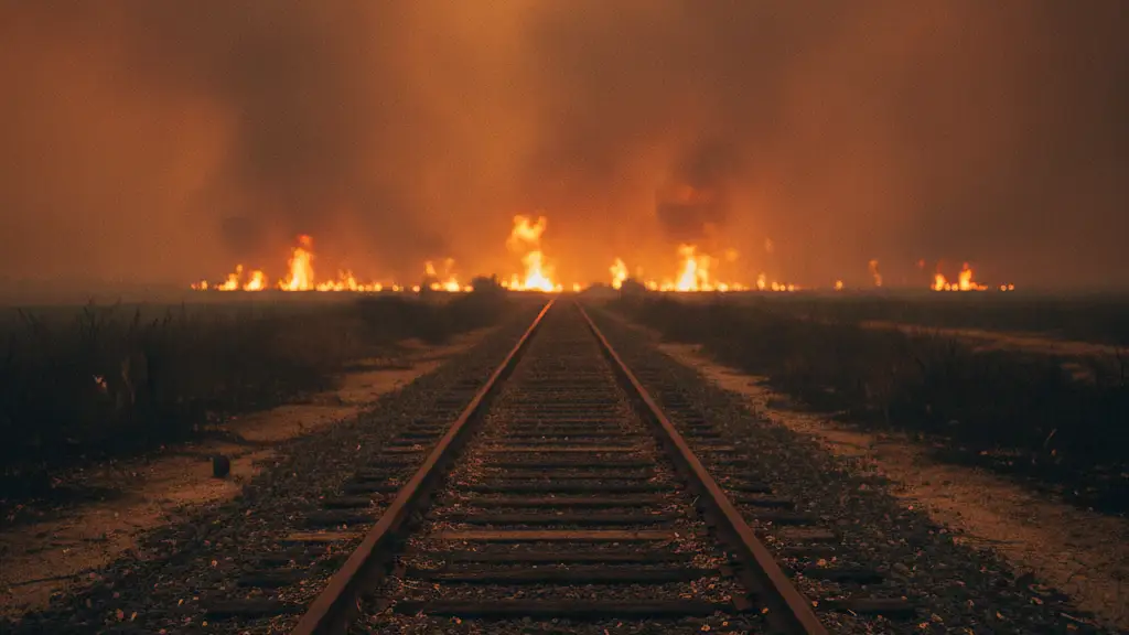 Train tracks disappearing into a thick, orange-red haze of wildfire smoke.