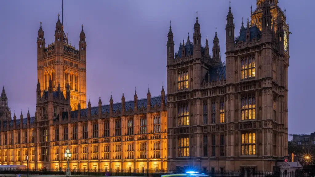 The Palace of Westminster at dusk with blurred police lights reflecting on the street.