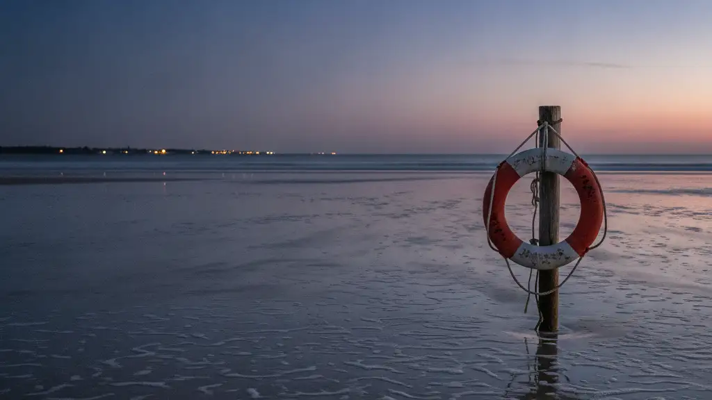 A lone lifebuoy on a post at a deserted beach at dusk, reflecting a somber mood.