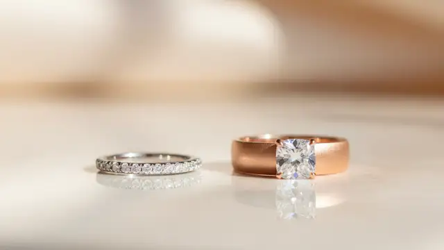 Two elegant wedding rings, slightly separated, on a reflective surface.