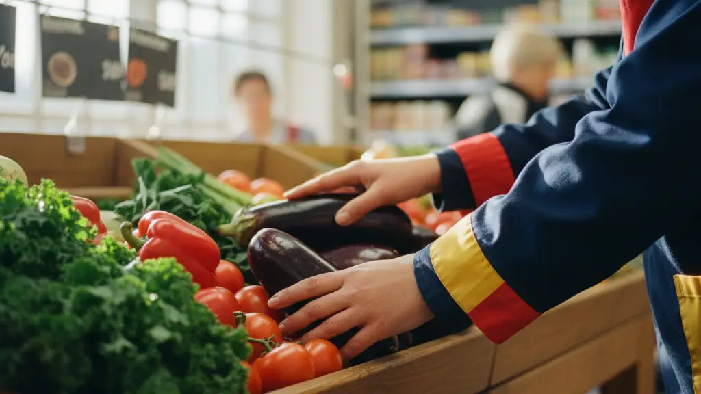 Close-up of a supermarket worker's hands in a navy uniform stocking fresh produce.