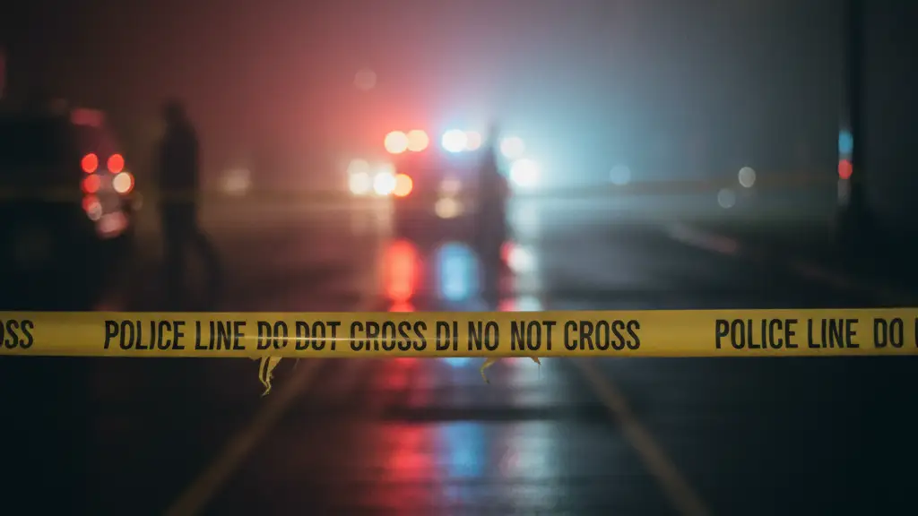 Police tape blocks access near flashing emergency lights at a distance.