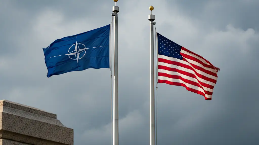 The NATO and United States flags flying together against a cloudy, dramatic sky.